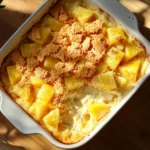 Pineapple casserole with cheese served in a white ceramic dish.